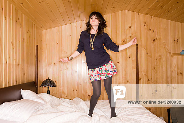 Junge Frau tanzt auf dem Bett