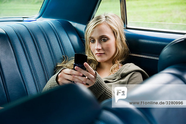 Young woman in car with cellphone