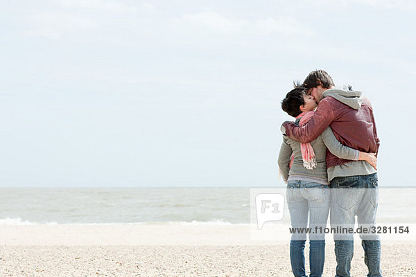 Junges Paar küsst sich am Meer