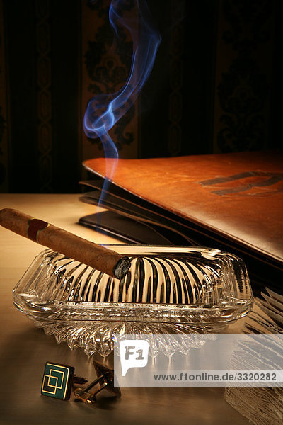 Brennende Zigarre im Aschenbecher auf einem Nachttisch