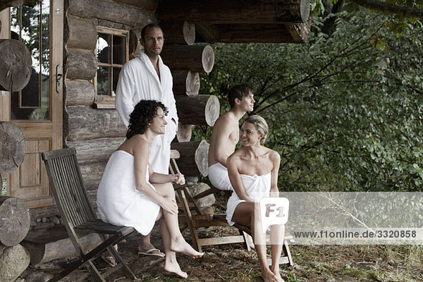 Vier Personen entspannen sich außerhalb der Sauna in einem Wellnessbereich.