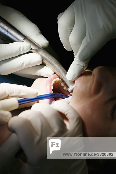 Nahaufnahme eines Zahnarztes und einer Zahnarzthelferin bei einer Patientin