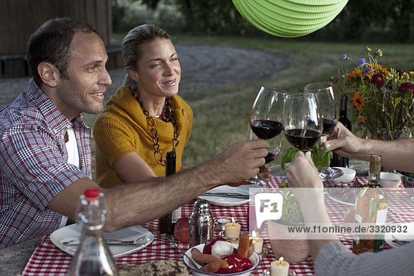 Four people at a dinner raising their wineglasses in a toast