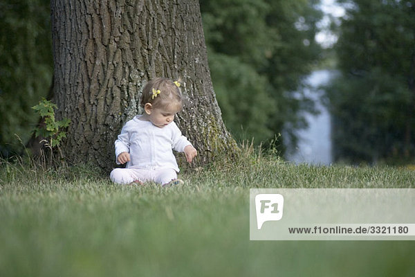 Ein kleines Mädchen unter einem Baum sitzend