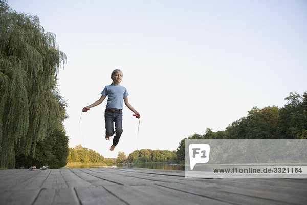 A girl skipping on a wooden jetty