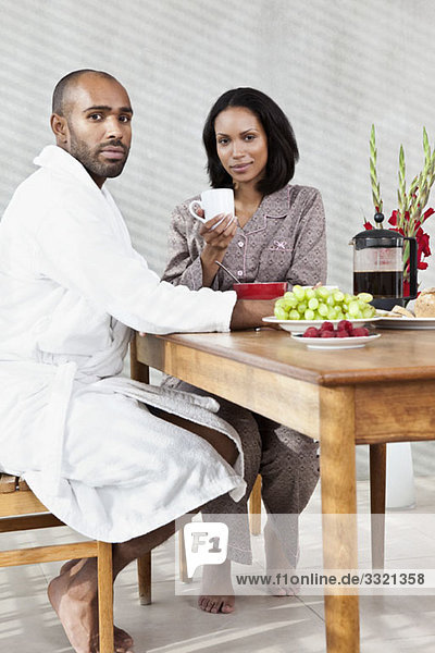 Ein junges Paar sitzt zum Frühstück an einem Tisch.