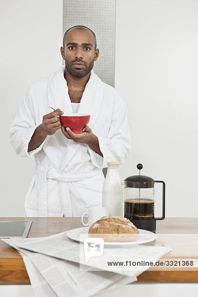 Ein Mann im Bademantel beim Frühstück.