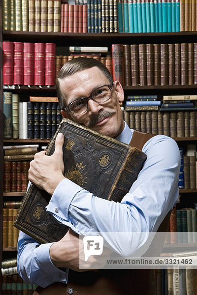 Ein Mann  der ein Buch fest an der Brust hält  glücklich in einer Buchhandlung.