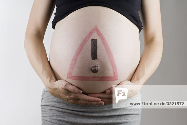 Ein Warnschild auf einem schwangeren Bauch  Mittelteil  Fokus auf den Bauch.