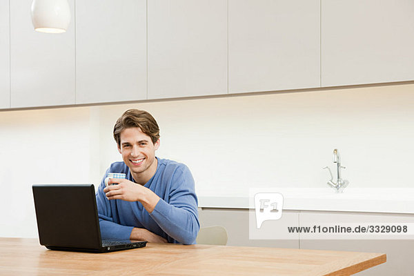 Junger Mann am Tisch sitzend mit Laptop