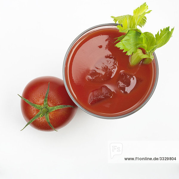 Glas Tomatensaft und eine ganze Tomate auf weißem Hintergrund
