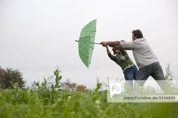 Paar mit Regenschirm im Windfeld