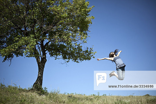 Frau beim Springen am Baum