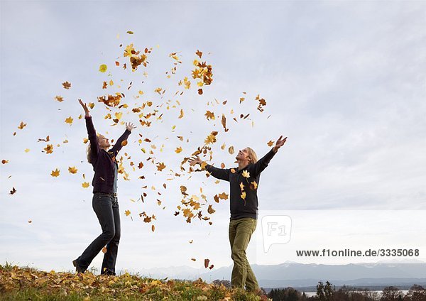 woman and man throwing autumn leaves