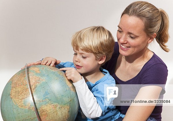 mother and son study globe