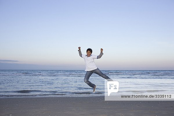 Ein Junge springt am Strand.