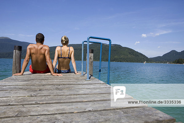 Ein Paar sitzt auf einem Pier am See.