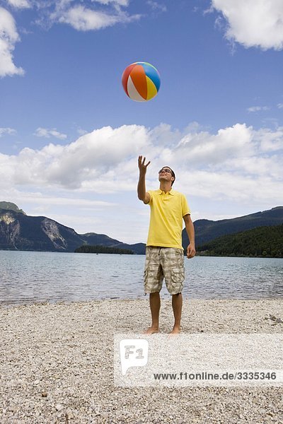 Ein junger Mann  der einen Strandball wirft.
