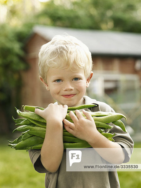 kleiner Junge mit Gartenprodukten im Freien