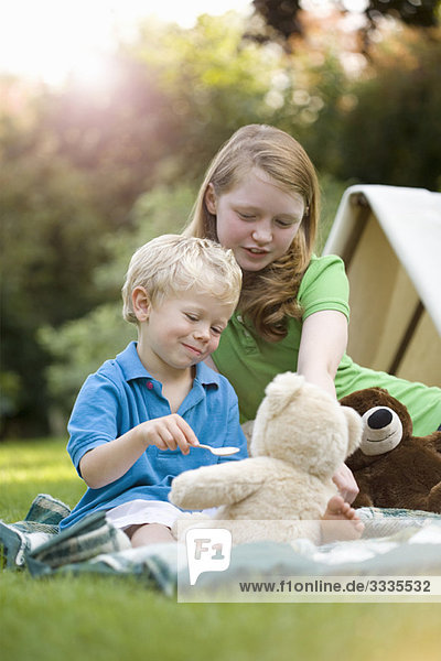 Zwei Kinder beim Füttern eines Spielzeugbären