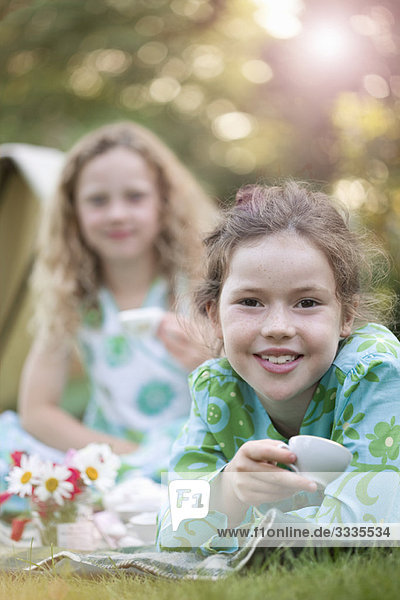 Zwei Mädchen lächeln beim Picknick.