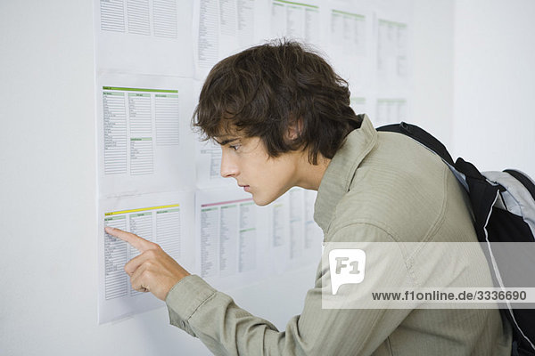 Male college student checking results posted on bulletin board