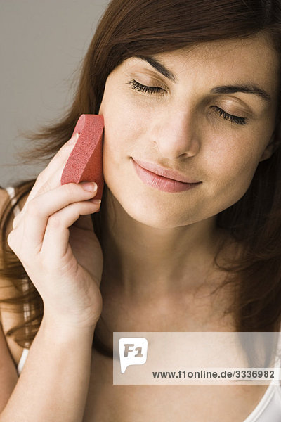 Young woman using cosmetic sponge