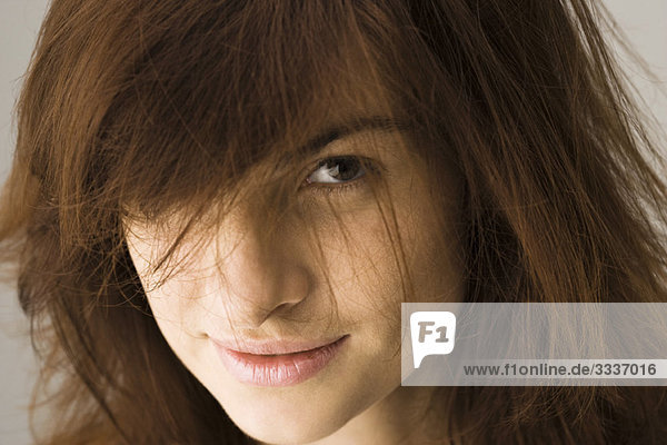 Junge Frau mit zerzaustem Haar sieht verführerisch in die Kamera  Porträt