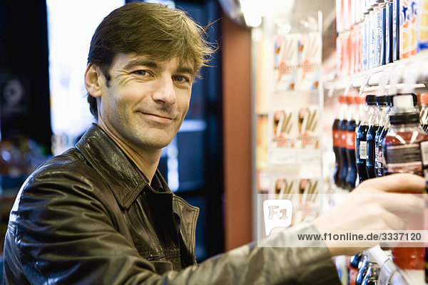 Man at soft drink cooler in convenience store