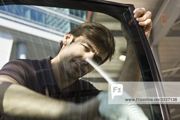 Mann reinigt Autotürfenster