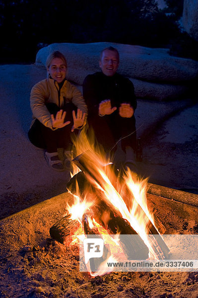 Paar wärmt sich bei Campingurlaub am Lagerfeuer auf