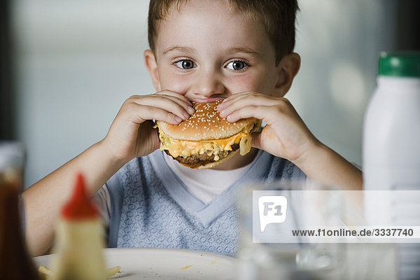 Kleiner Junge isst Cheeseburger