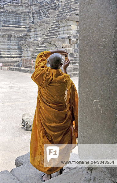 Buddhistischer Mönch schaut auf ein Handy  Angkor  Kambodscha  Rückansicht