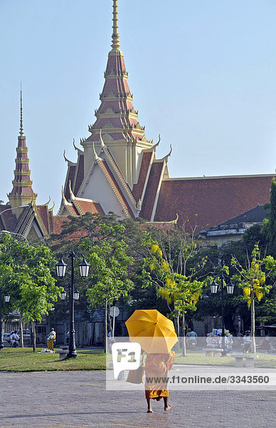 Buddhistischer Mönch mit Sonnenschirm  Silberpagode im Hintergrund  Phnom Penh  Kambodscha