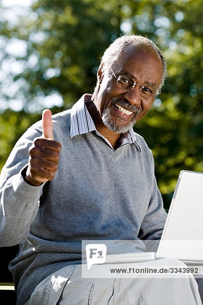 Senior man using a laptop in a park  Sweden.
