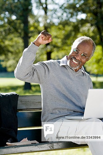 älterer Mann mit einem Laptop in einem Park  Schweden.