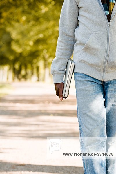 älterer Mann zu Fuß in einem Park mit einem Laptop  Schweden.