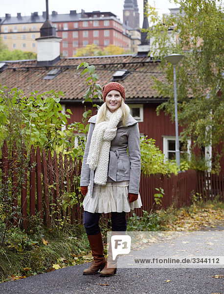 Eine Frau stehend von einem roten Zaun im Herbst  Schweden.