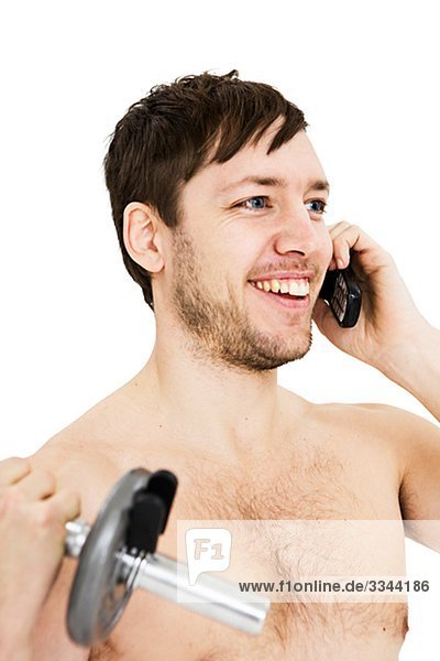 Junger Mann Gewichte zu heben und mithilfe eines Mobiltelefons.