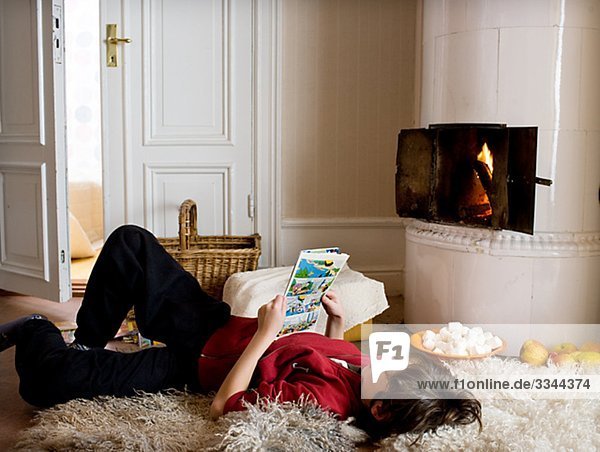 Boy reading by a tiled stove  Sweden.