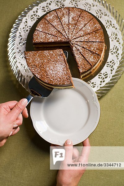 Hand nehmen einen großen Teil ein Schokoladenkuchen.