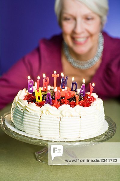 ältere Frau mit einem Geburtstagskuchen.