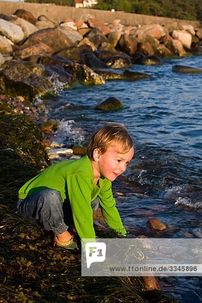 Ein Junge sitzt am Meer  Schweden.