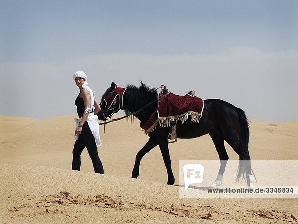 Frau mit einem Pferd in der Wüste Tunesien.