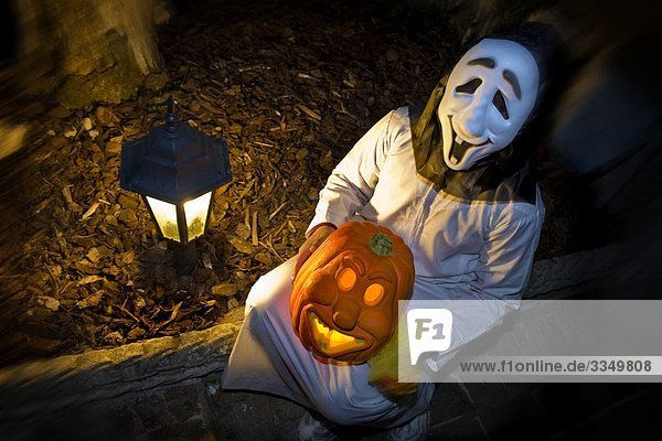 Person in Halloween costume holding pumpkin