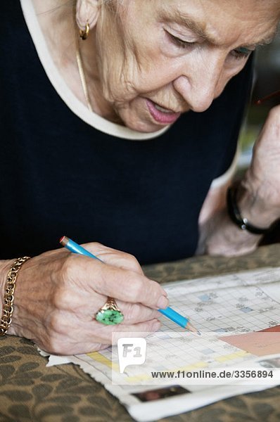 Ältere Frau löst Kreuzworträtsel