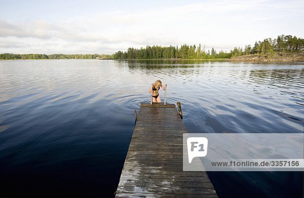 Woman entering water from pier