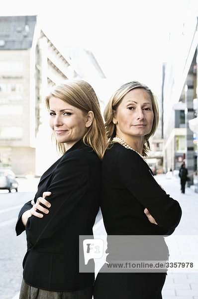 Two businesswomen standing back-to-back