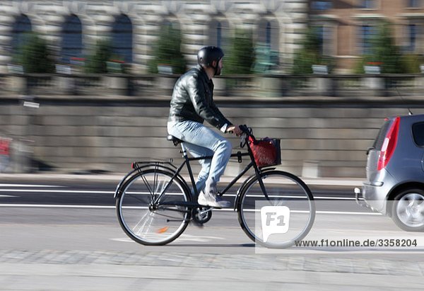 Mann mit dem Fahrrad die Straße hinunter