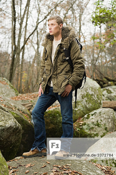 Junger Mann auf Steinen im Wald stehend